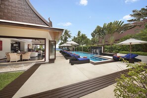 Un resort moderno con piscina, sillas de descanso y un área de estar cubierta.