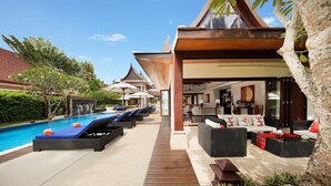 A resort with a swimming pool, lounge chairs, and a covered seating area with sofas and a coffee table. - Baan Samlarn (Koh Samui)