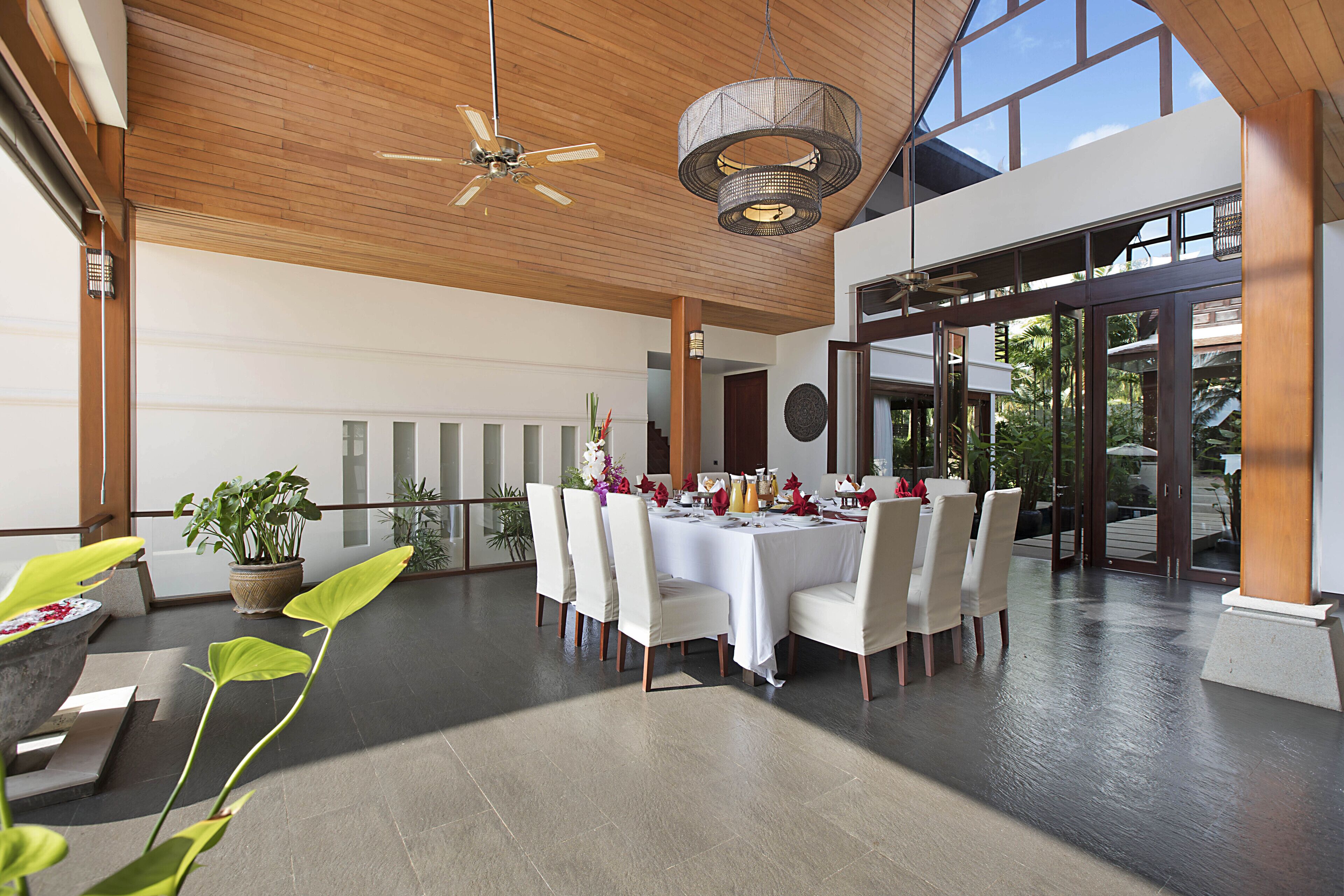 A spacious dining area with a high ceiling, modern lighting, and a view of the outdoors.