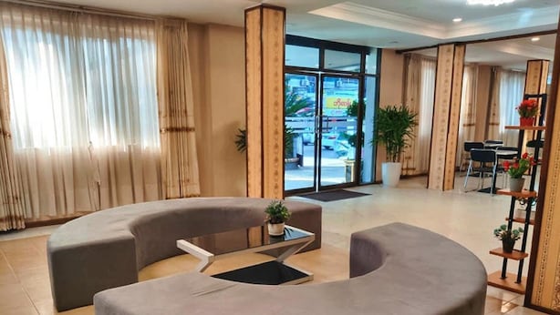 Eine moderne Lobby mit einer gebogenen Sitzecke, einem Couchtisch und Blick auf die Straße durch große Fenster.