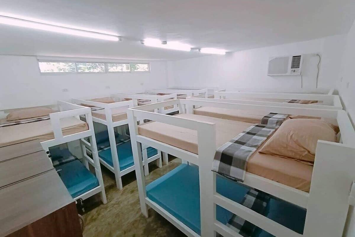 Un dormitorio con literas, una ventana y un equipo de aire acondicionado.
