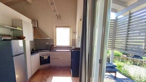 Una cocina moderna con piso de madera, horno empotrado y un amplio ventanal corredero que da a una terraza.
