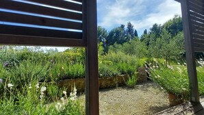 Un espacio exterior cubierto con suelo de madera y vistas a un jardín con diversas plantas y flores.