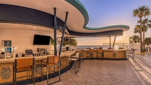 A curved bar area with seating, a flat-screen TV, and a tiled floor. - Daytona Beach | Beach & Pool Access | 2BR Deluxe (Daytona)