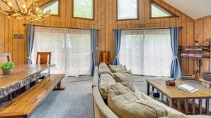 Een gezellig cabin interieur met een houten eettafel, bankjes, een bank en een kroonluchter.