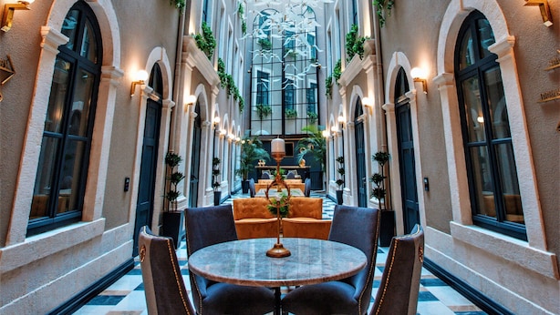 A hotel corridor with a checkered floor, arched windows, and a central seating area with a round table and chairs. - Ferman Port Hotel - Special Class (Istanbul)