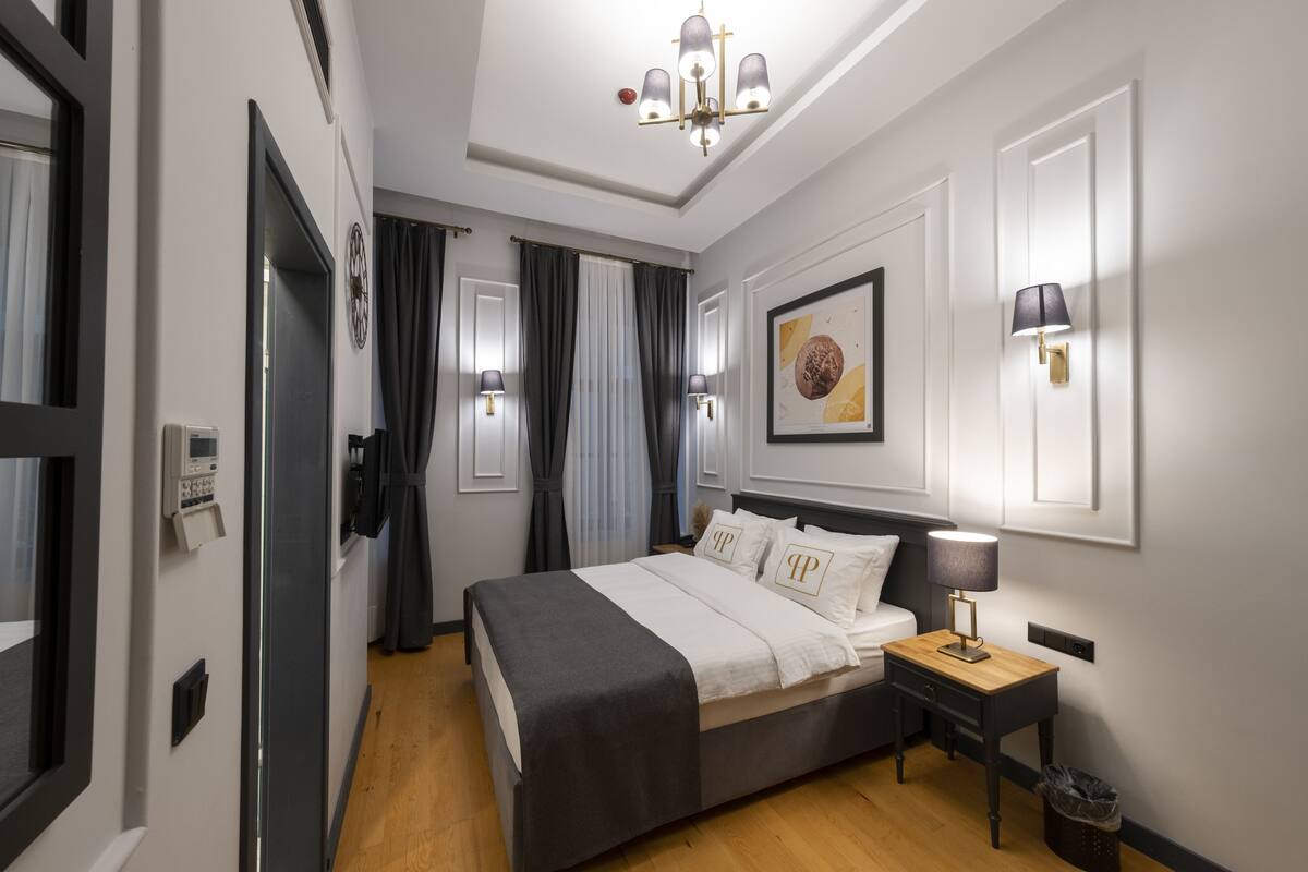 A modern bedroom with a bed, bedside tables, a lamp, and a wall-mounted artwork.