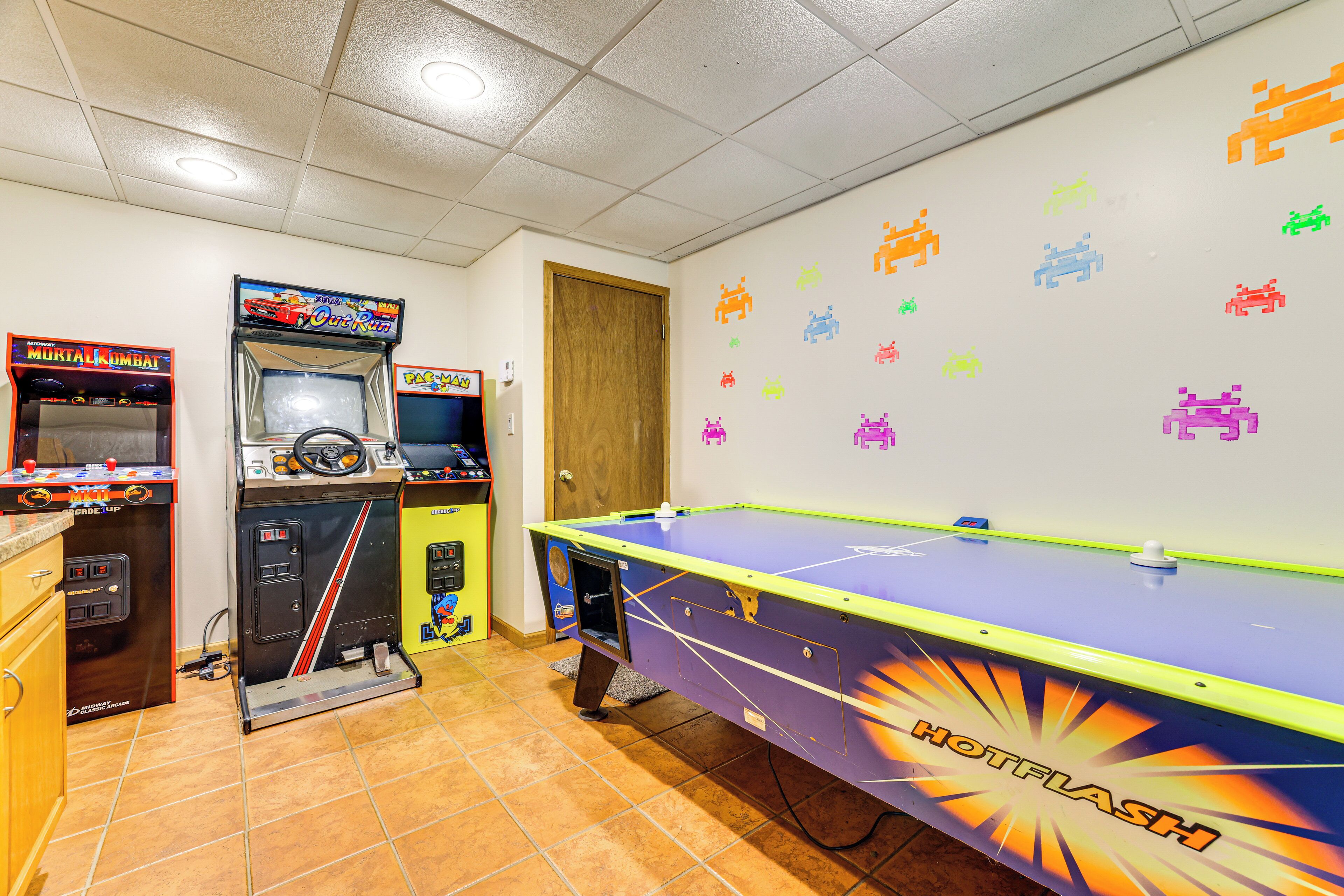 Une pièce équipée d’une table de billard, de jeux d’arcade et dont un mur est décoré d’autocollants sur le thème de l’espace.