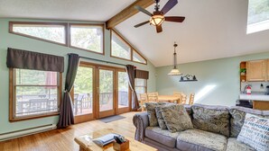 Un salon spacieux doté d’un plancher en bois, d’un canapé agrémenté de coussins à motifs, d’une table basse en bois et d’un ventilateur de plafond.