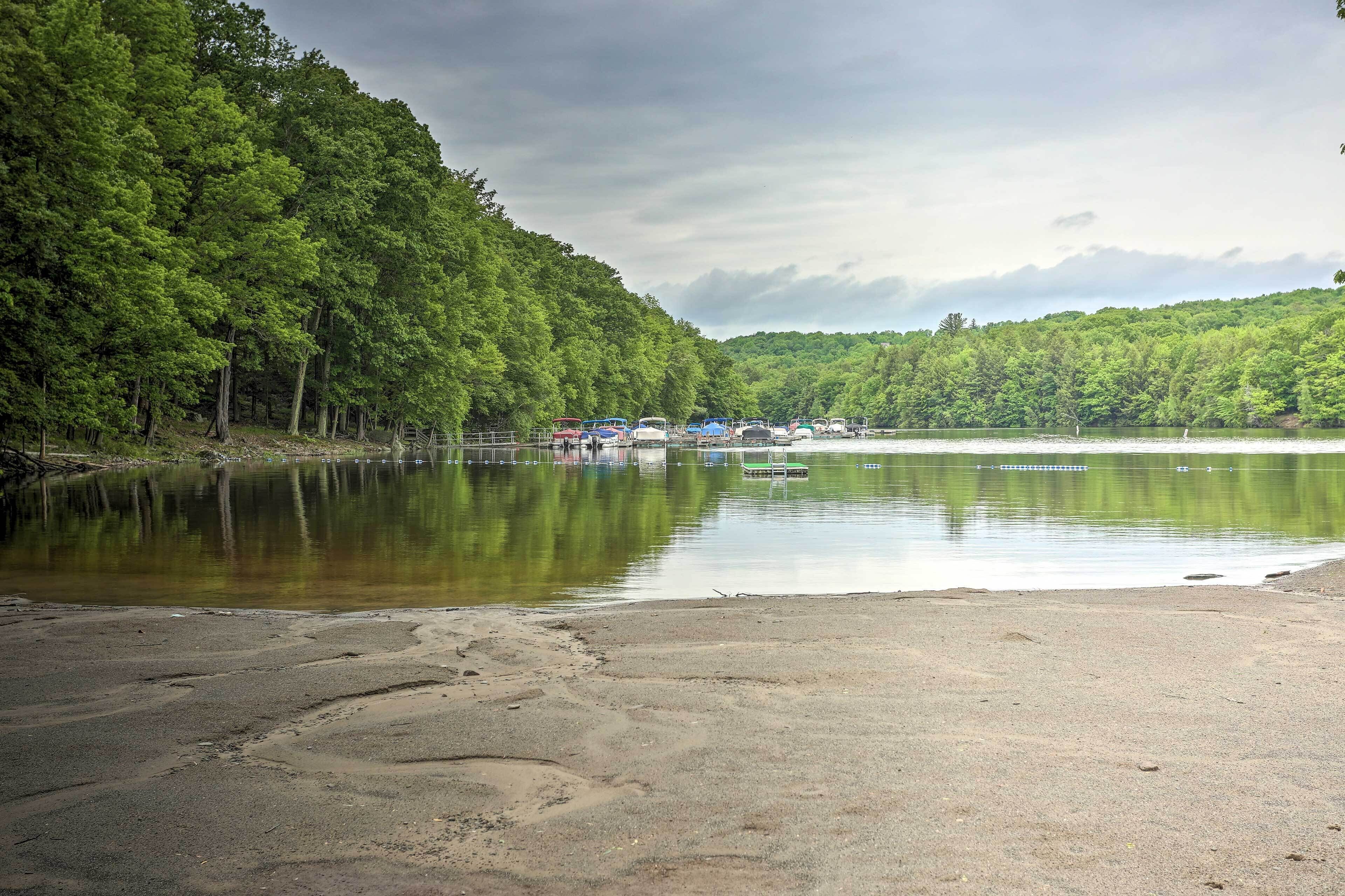 Une vue sur le lac, avec une plage de sable, une forêt dense et plusieurs bateaux amarrés près du rivage.