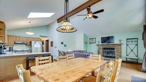 Un vaste espace de vie comprenant une grande table à manger en bois, des chaises en bois, une cheminée et un téléviseur.