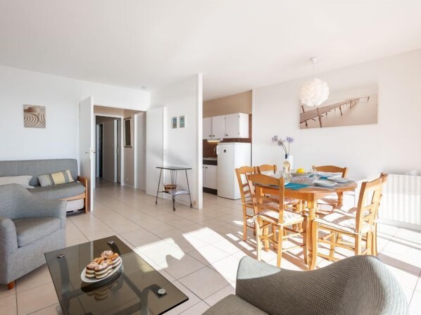 A modern apartment with a living room, dining area, and kitchen.