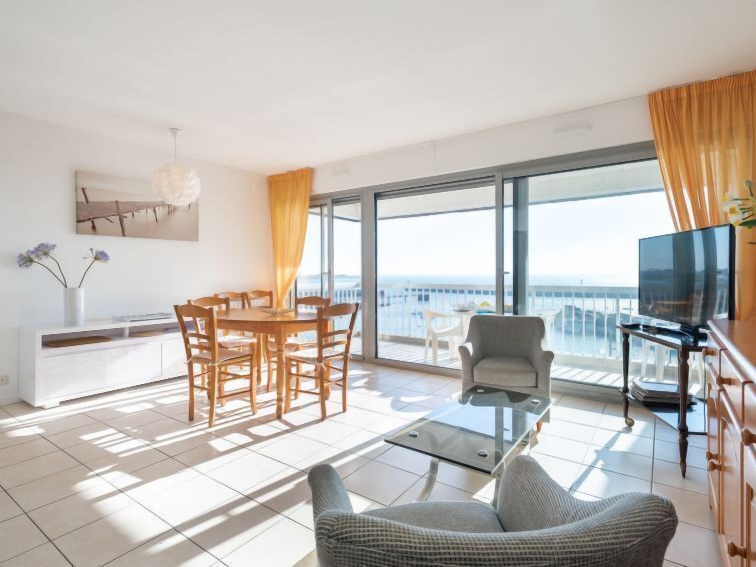 Een moderne woonkamer met een balkon, een eethoek en een televisie.