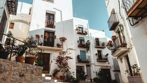 A narrow street with white buildings, balconies with potted plants, and a cobblestone path. - Appart 4/6 people sea and mountain view, outdoor and inter heated swimming pool (Peniscola)