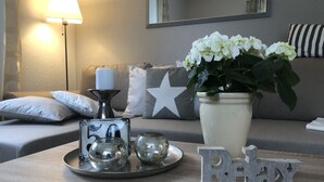 Un soggiorno con divano, tavolino, lampada, un vaso con fiori e oggetti decorativi.