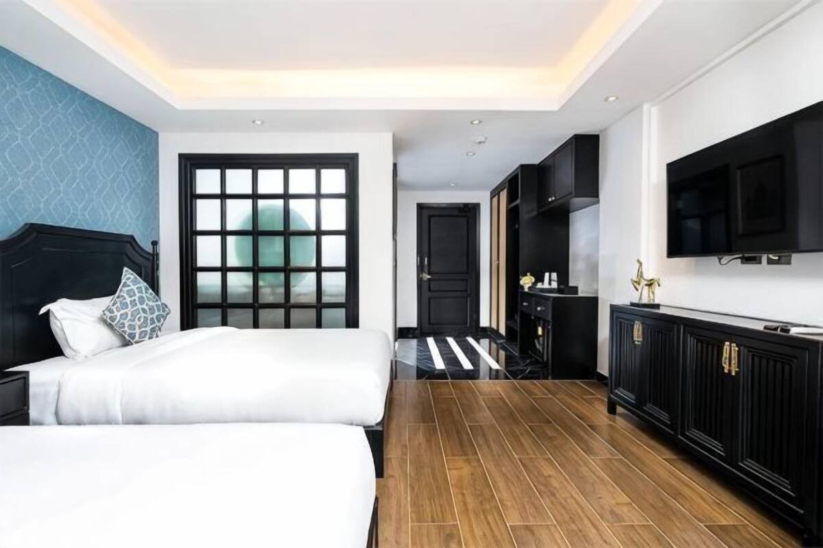 Una habitación de hotel con cama, escritorio, televisor y armario.