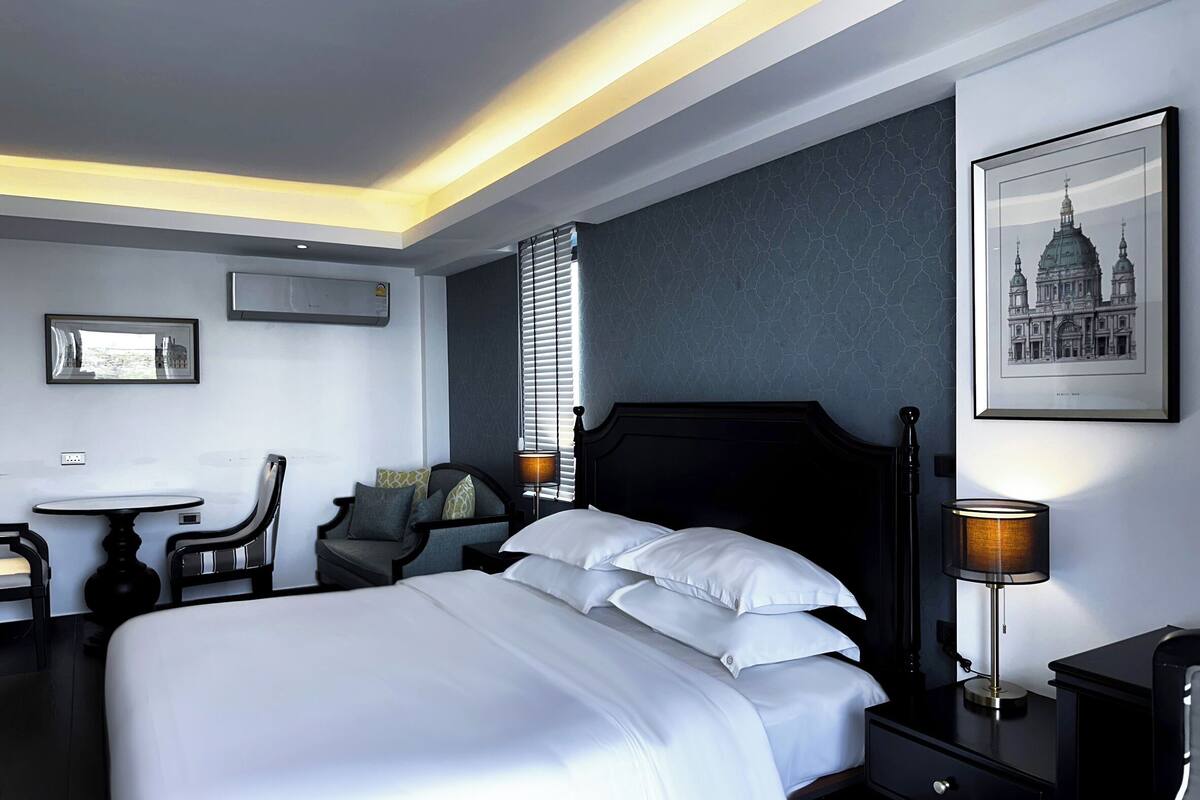 Habitación de hotel con una cama grande, un escritorio, una silla y un cuadro en la pared.