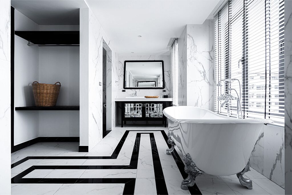 A modern bathroom with a freestanding bathtub, a large mirror, and a black and white patterned floor.