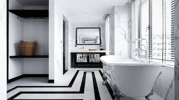 A modern bathroom with a freestanding bathtub, a large mirror, and a black and white patterned floor.