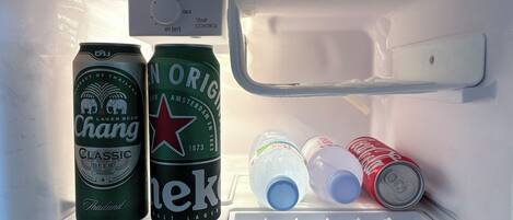 Un réfrigérateur contenant deux canettes de bière, une bouteille et une canette de Coca-Cola.