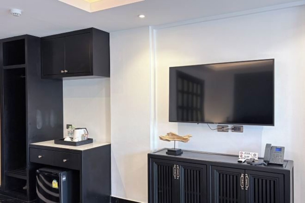 Una sala moderna con un televisor de pantalla plana montado en la pared, un mueble de entretenimiento negro debajo y un horno empotrado.