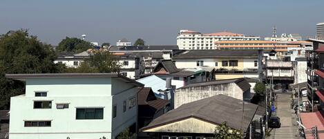 A multi-story building with a flat roof and a mix of residential and commercial structures in the background.