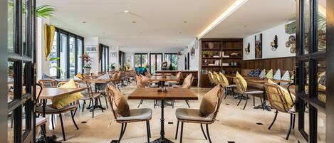 Un comedor amplio con varias mesas y sillas, ventanas grandes y un diseño de interiores moderno.