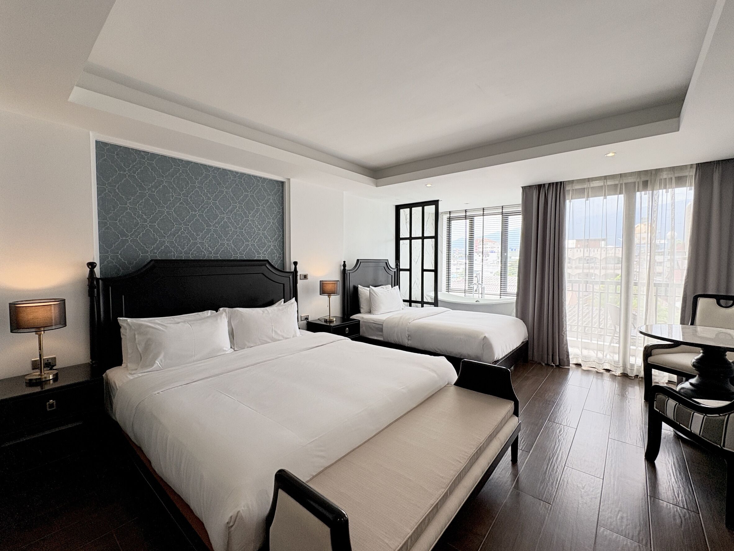 A hotel room with two beds, a desk, and a view of the city.