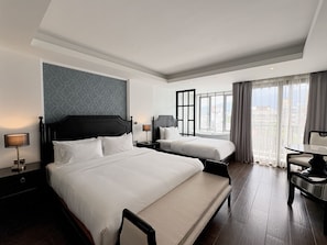 A hotel room with two beds, a desk, and a view of the city. - Glory Boutique Suite (Chiang Mai)