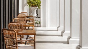 A corridor with a row of wicker chairs and a table, a potted plant, and a staircase leading to an upper level. - Glory Boutique Suite (Chiang Mai)