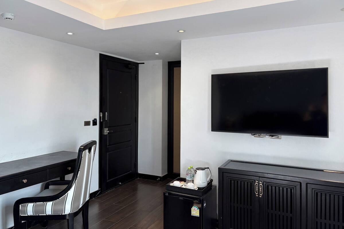 Habitación de hotel moderna con una televisión de pantalla plana, un escritorio, una silla y un minibár.