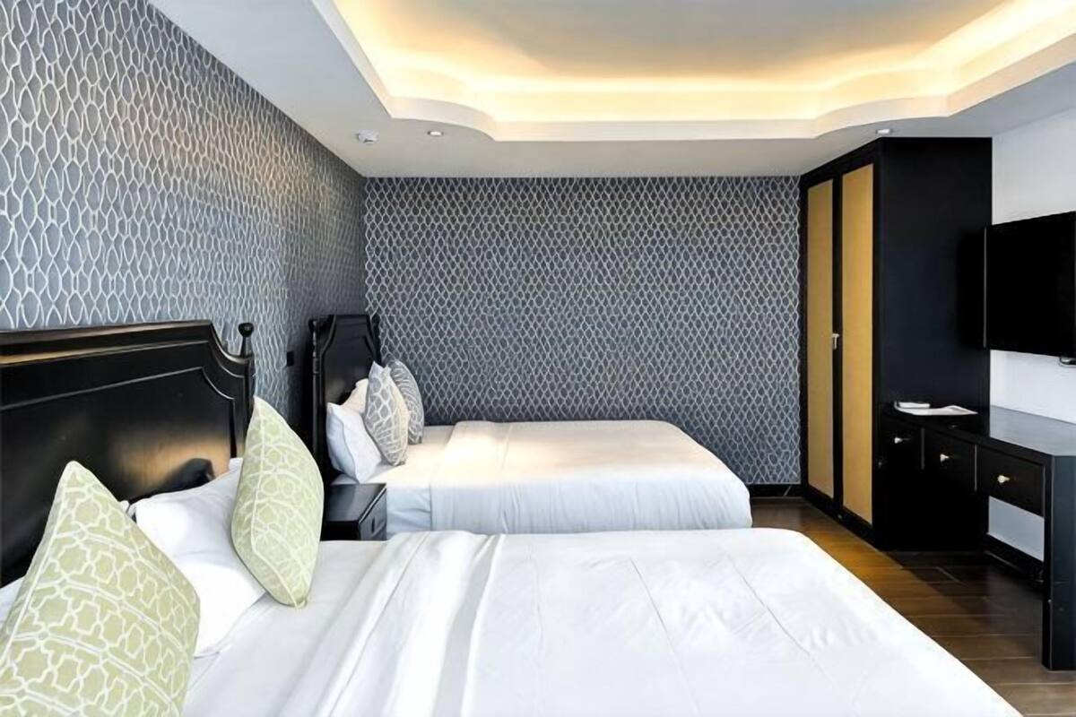 Una habitación de hotel con dos camas, un escritorio y un televisor.