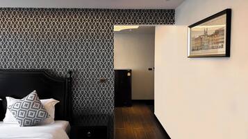 Una habitación de hotel moderna con papel tapiz estampado, un cuadro enmarcado de un paisaje urbano y suelo de madera.