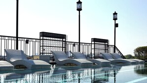 A pool area with lounge chairs and a metal fence. - Glory Boutique Suite (Chiang Mai)