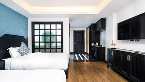 Una habitació d'hotel moderna amb un llit gran, un escriptori, una televisió i vista a l'exterior.