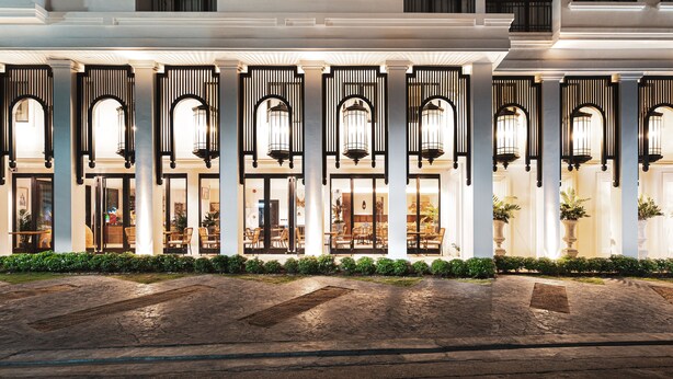 A hotel facade with multiple arched windows, a central entrance, and a series of columns. - Glory Boutique Suite (Chiang Mai)
