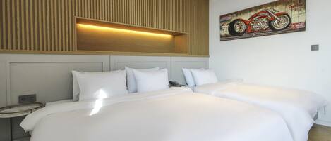 A hotel room with two beds, a wooden panel wall, a mounted motorcycle artwork, and a bedside table with a phone.