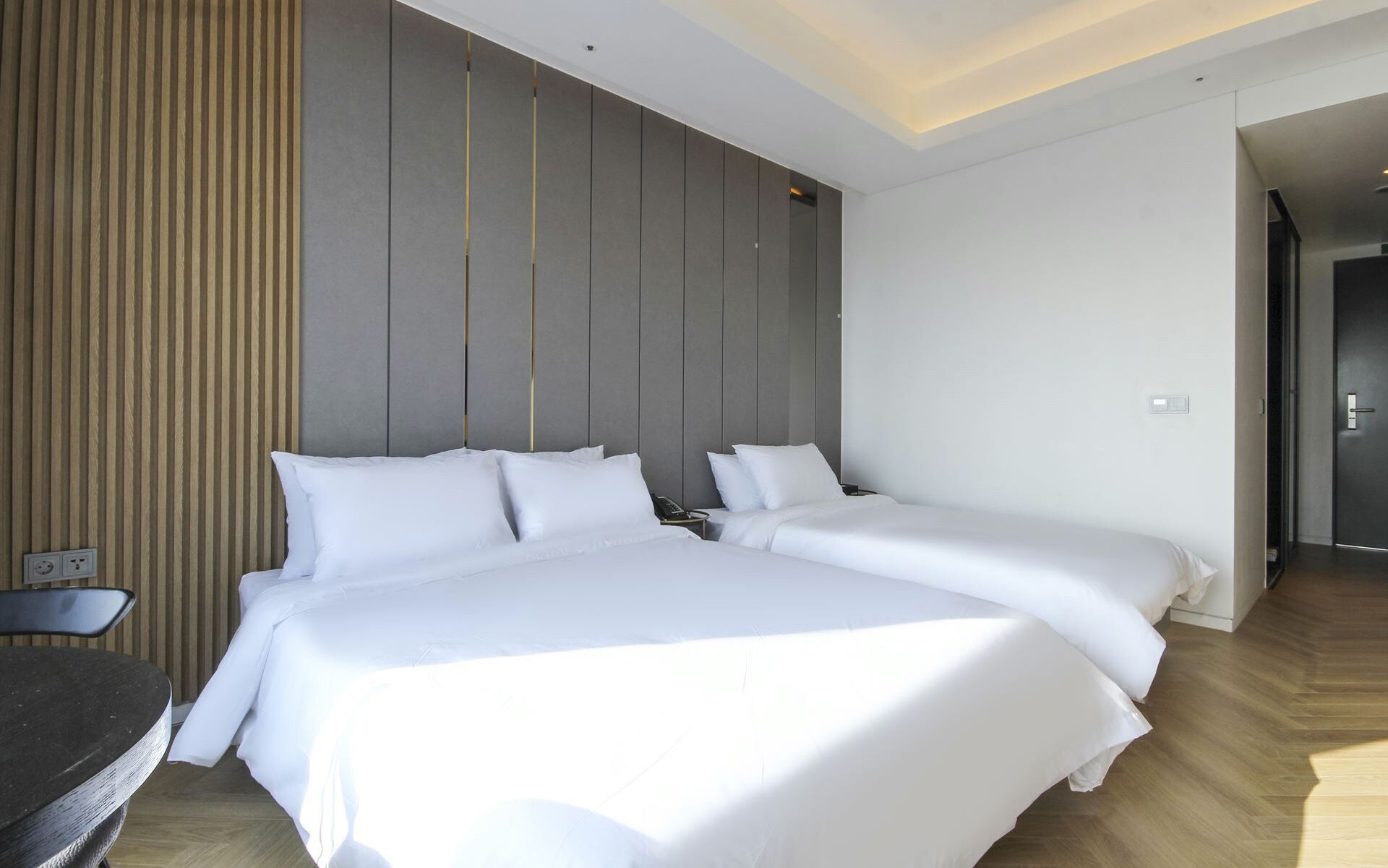 A modern hotel room with a large bed, bedside tables, and a desk.