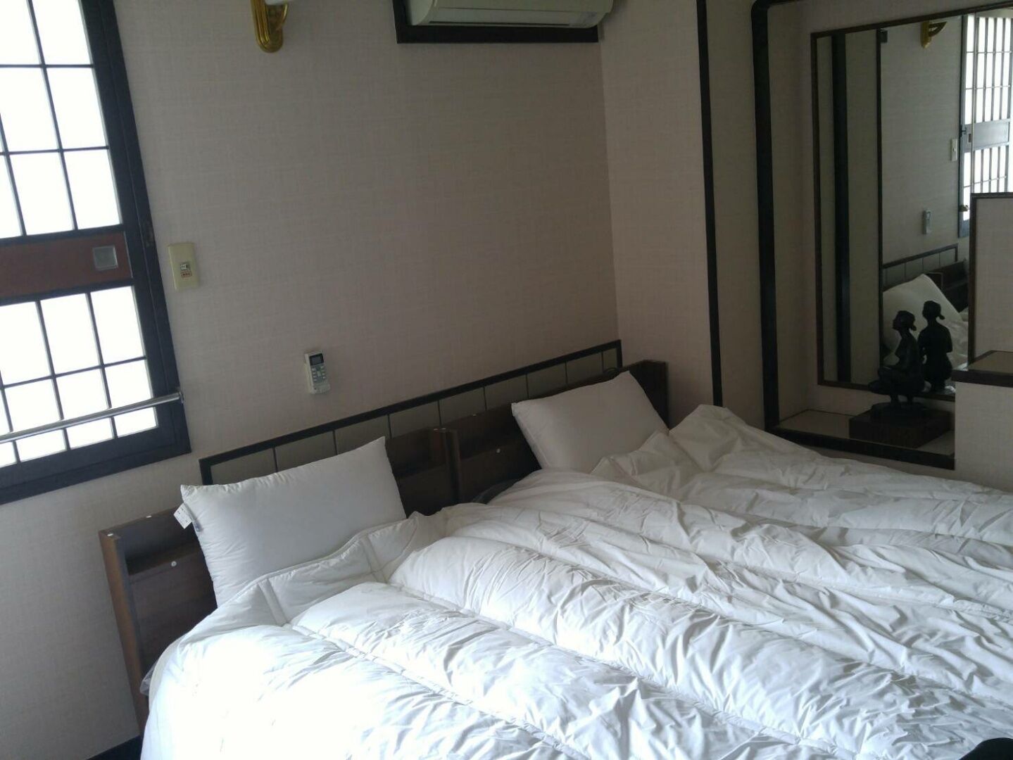 Ein Hotelzimmer mit Bett, Nachttisch, Wandtelefon und großem Spiegel.