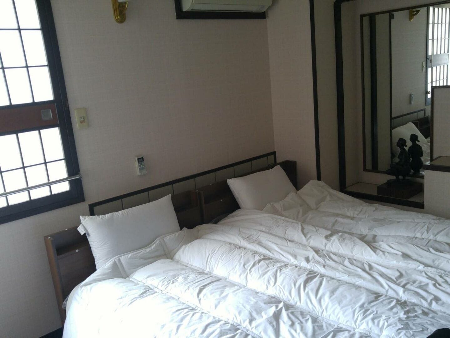 Een hotelkamer met een groot bed, een nachtkastje, een spiegel en een raam.