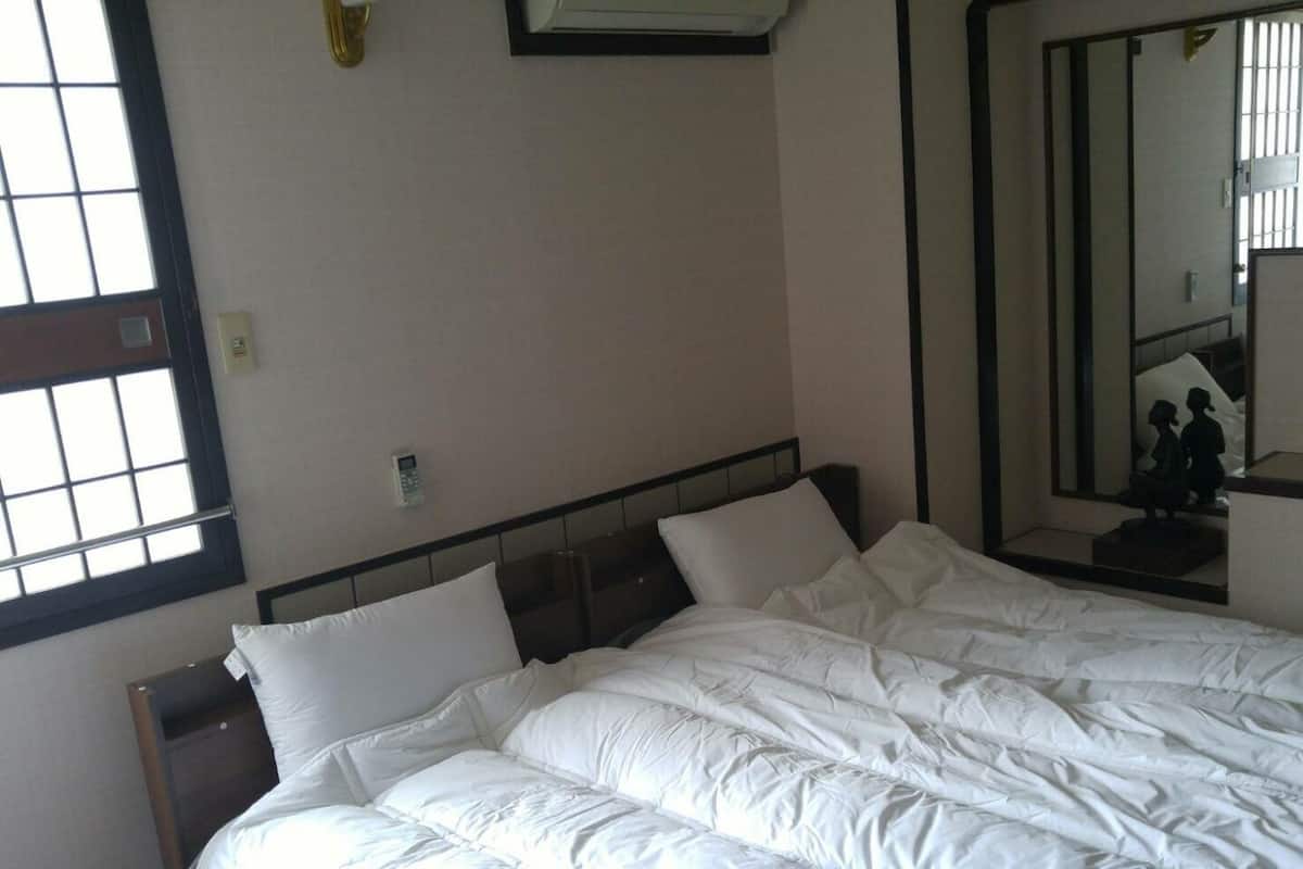 Een hotelkamer met een groot bed, een nachtkastje, een spiegel en een raam.