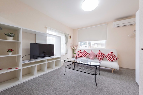 A modern living room with a flat-screen TV, white sofa, and a coffee table.