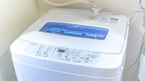 A compact, white, front-loading washer and dryer unit with a digital control panel, a hose connection, and a power cord. - Garden Otsuka 504 (Tokyo)