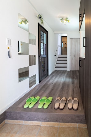 A hallway with a wooden floor, a door with a decorative glass panel, and a staircase leading to another room. - Butterfly Paradise Hakone-Yumoto (Hakone)