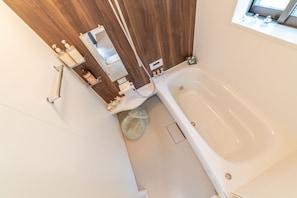 A bathroom with a bathtub, a wooden vanity, and a window. - Butterfly Paradise Hakone-Yumoto (Hakone)