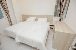 A neatly made bed with white linens, a wooden headboard, and a wooden nightstand with a lamp.