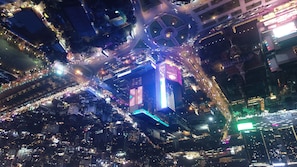A nighttime aerial view of a cityscape with illuminated buildings, roads, and a roundabout.