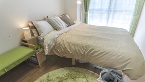 Quarto bem arrumado com cama, mesa de cabeceira, abajur e um pequeno banco.