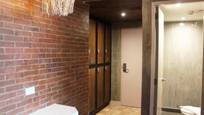 A bathroom with a brick wall, a white sink, and a shower area. - Connector Hostel (Makati)