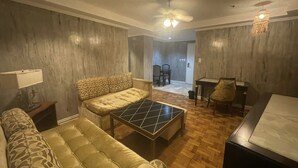 A living room with a sofa, a coffee table, and a dining area with a chair and table. - Connector Hostel (Makati)